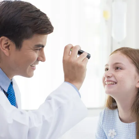 A doctor checks a girl for symptoms of concussion.