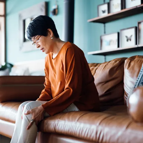 Woman Sitting on her couch clutching her leg with pain