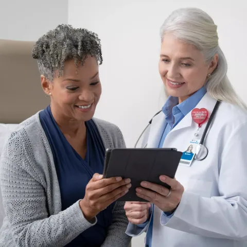 Doctor and patient holding tablet in medical office.
