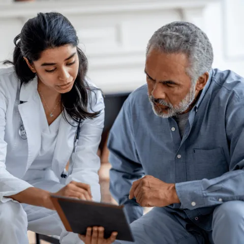 Female doctor showing male patient his test results on a tablet.