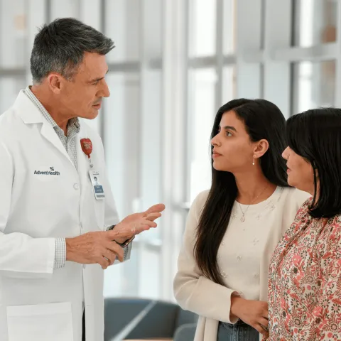 A Doctor Speaks to an Adult Patient and Her Mother in the Lobby of a Hospital