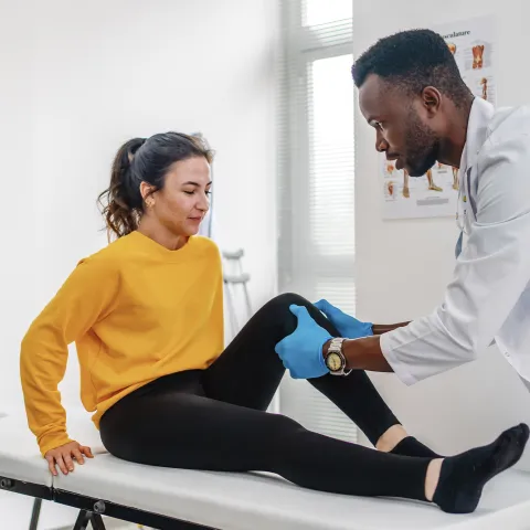 Doctor examining female patient's leg