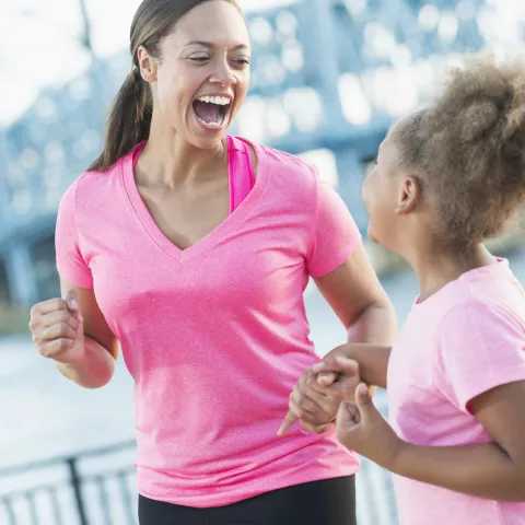 A mother and daughter are jogging together outside.
