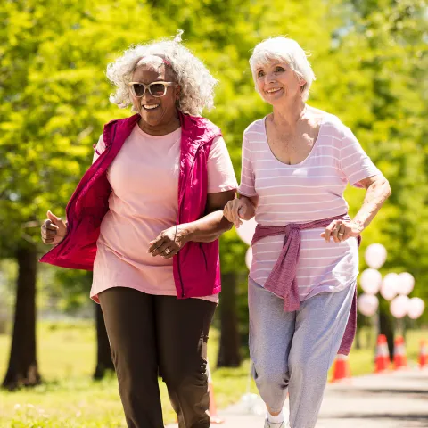 Two elderly women walking in the park.