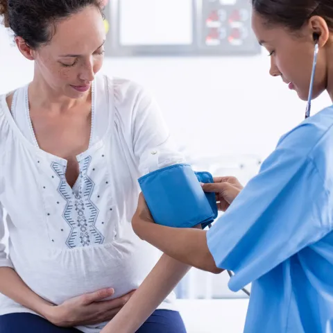 Pregnant woman gets her blood pressure checked at the doctor.