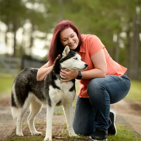 Woman petting her dog while outdoors.