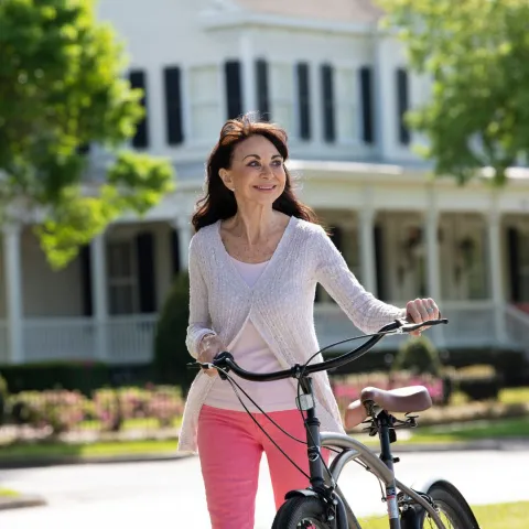 Older woman holding her bike.
