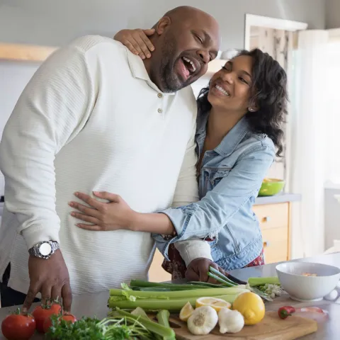 A couple hugging each other while cooking on the kitchen