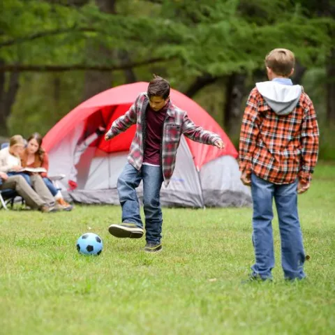 Two boys play soccer on a family camping trip