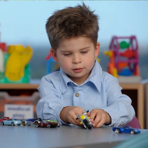 A boy plays with a toy motorcycle.