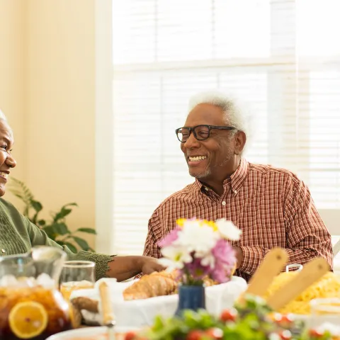 An elderly couple sitting at the table, getting ready to eat lunch. 
