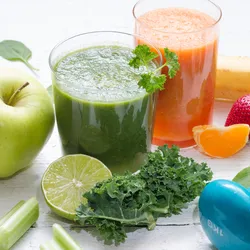 Healthy drinks, fruit, a weight, and a tape measure on a table.