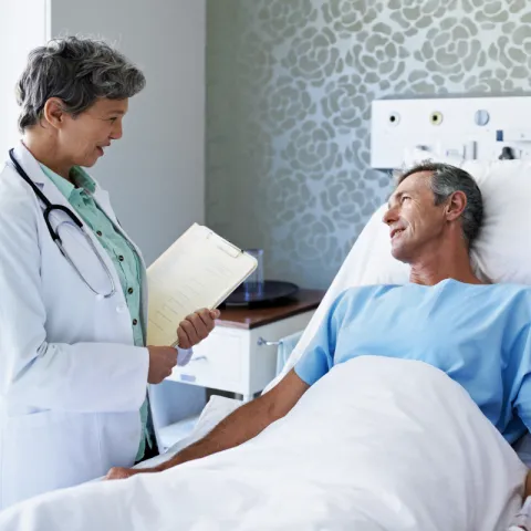 Doctor speaks to a patient who is lying in a hospital bed