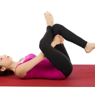 A woman lies on her back, stretching. 