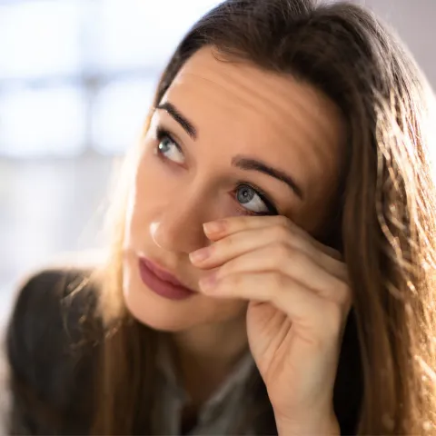 A woman rubs her eyes.
