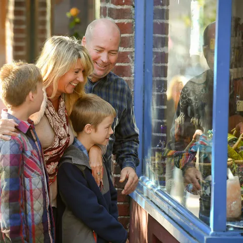 Parents with grandchildren looking through a store window.