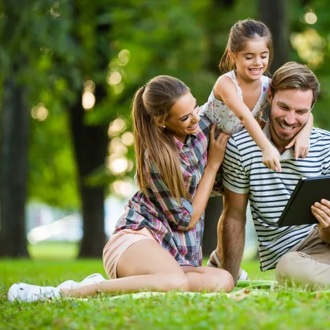 Happy family in park reading a tablet 