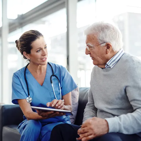 Nurse talking with older man at the hospital.
