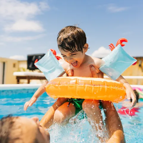 Photo of a little boy having fun with his father while swimming in the pool.