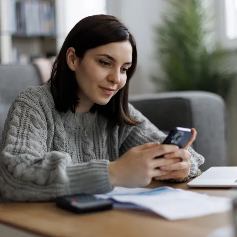 A woman checks her phone while sitting at a table.
