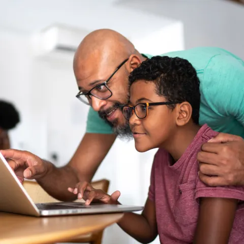 A father and son look at a laptop together.