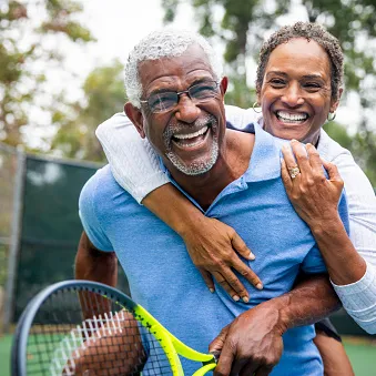 woman hugging man with tennis racket