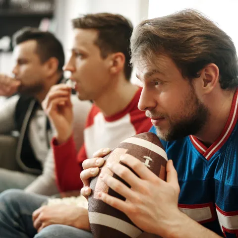 A group of men watch a football game excitedly.