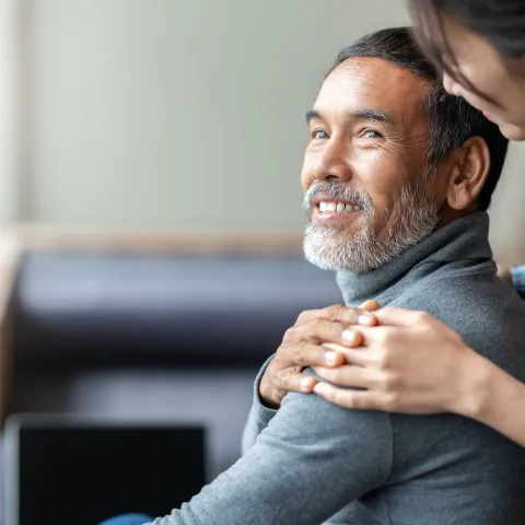 A daughter hugs her father from behind.