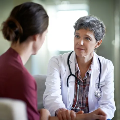 A female doctor comforts a young woman in her office