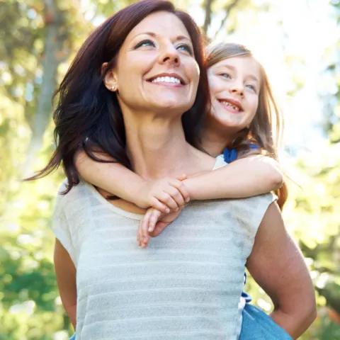 A woman gives her daughter a piggy back ride.