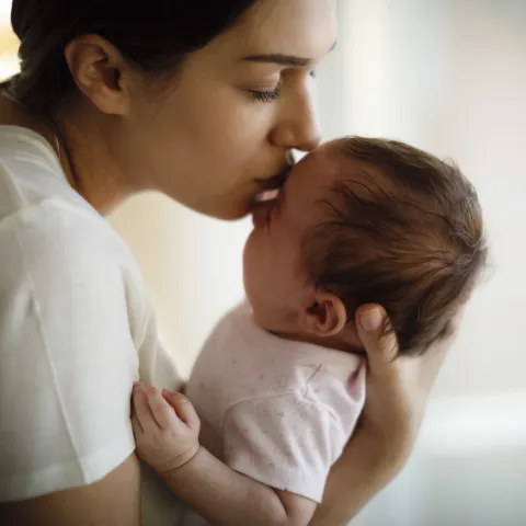 A mom kissing her infant.