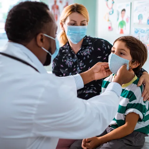 Mother and son at a doctor's office while wearing masks.