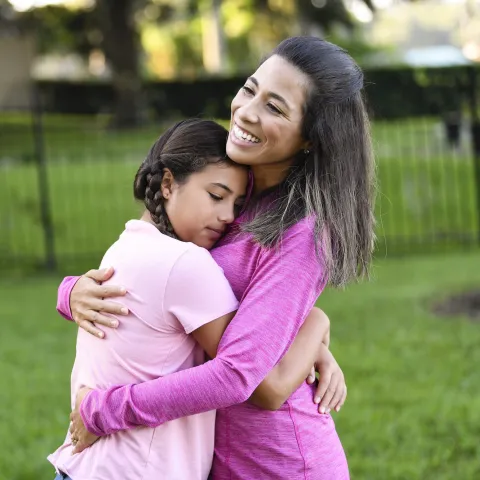 A mother and daughter hugging. 