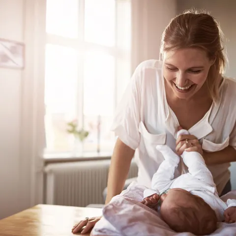 A new mom tickles her infant's feet.