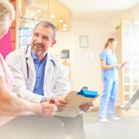 A patient speaks with her doctor in the waiting room.