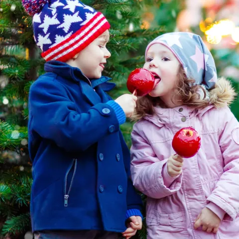 Two children at candy apples near the holidays.