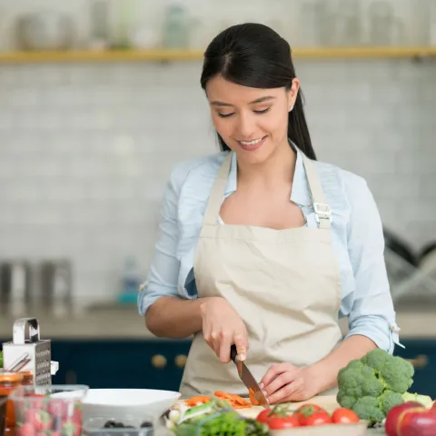A Young Woman Chops Veggies in the Kitchen