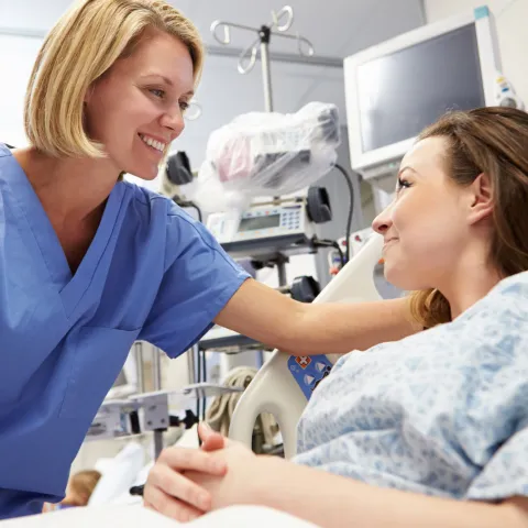 A woman on her hospital bed talks with her doctor.