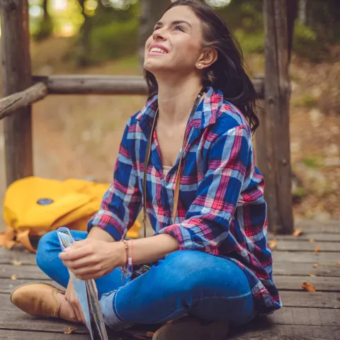 A woman takes a deep breath while sitting outside.