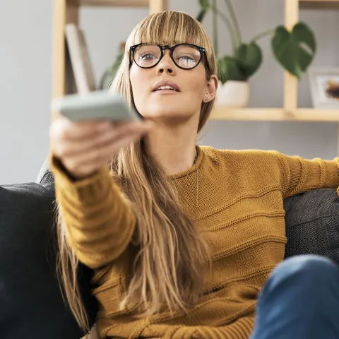 Woman at home turning on her tv.
