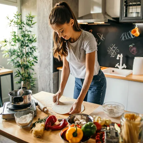 A young woman cooking in her kitchen.