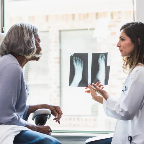 A patient and physician looking at foot x-rays