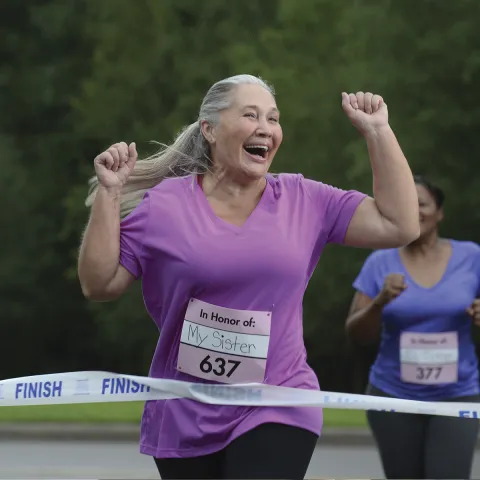 A senior woman crossing the finish line in a race