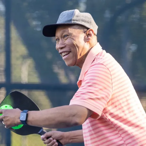 An older man playing Pickleball