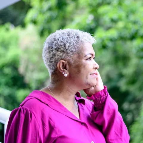 An older woman talking on the phone outdoors.