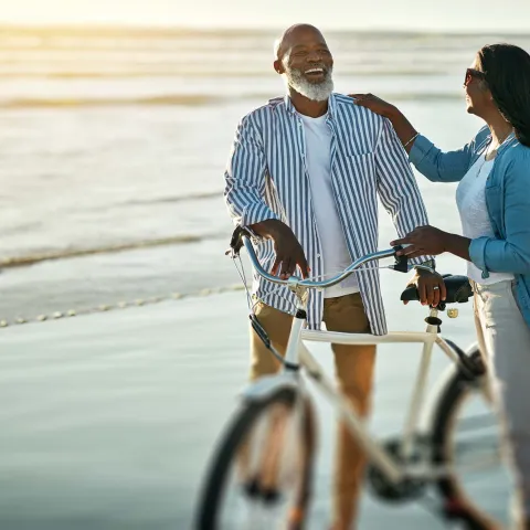 Couple smiling with bicycle on beach