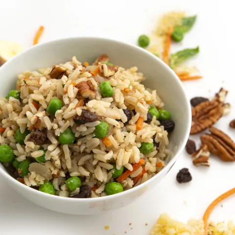 Bowl of pilaf on white counter with pecan garnish