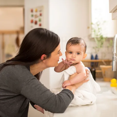 A mom drying her baby in the kitchen's counter-top.