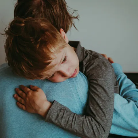 A mother holding and comforting her son.