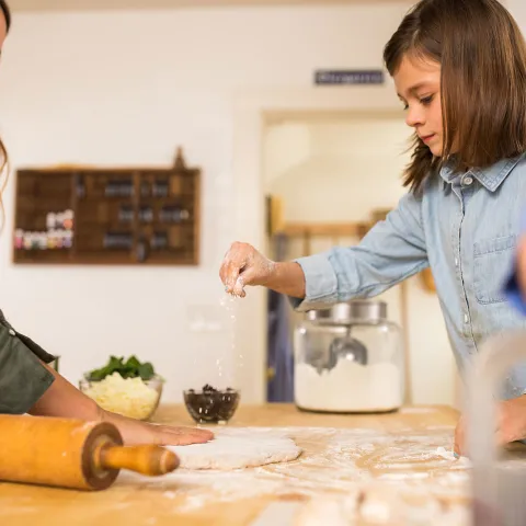 A mother cooking with her kids in the kitchen.